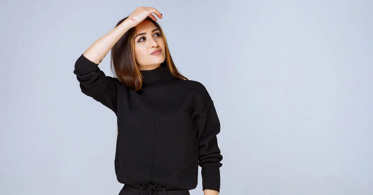 Woman wearing a black sweater against a light background